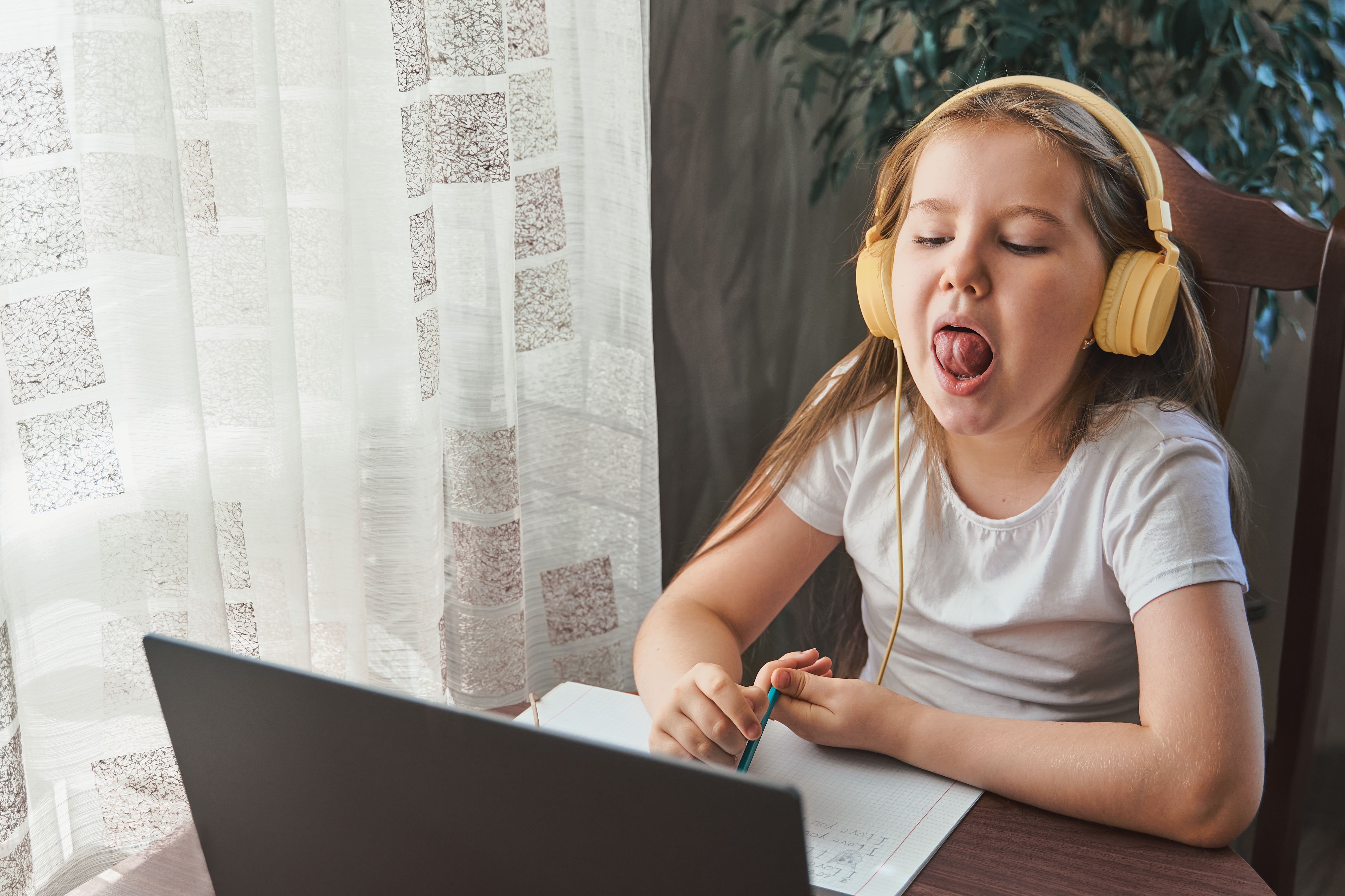 Speech training concept. Little girl uses a laptop to study at home with a teacher
